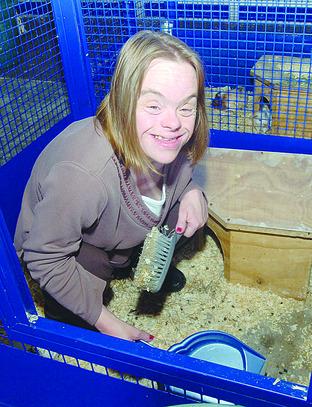 Client Sue Norledge cleans out the rabbits.