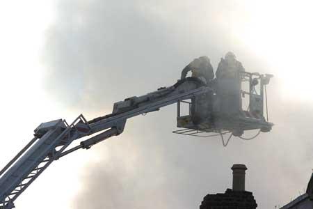 Firefighters above the burning buildings.