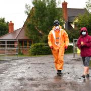 Karen Wright (left), Director of Public Health for Herefordshire CCG, sanitising before opening a gate to give a press statement outside Rook Row Farm in Mathon, near Malvern, Herefordshire, where there have been 73 positive cases of coronavirus