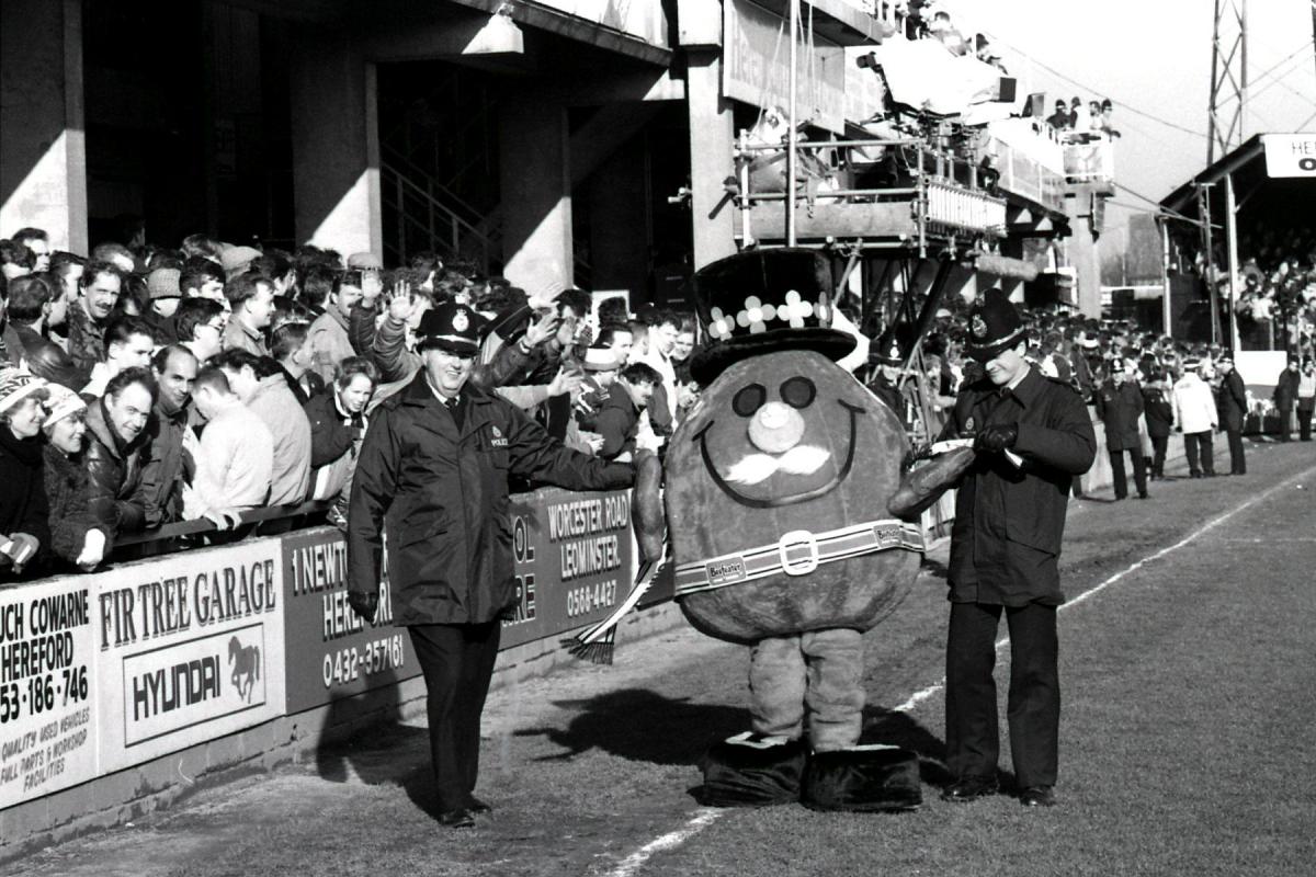 A Beefeater mascot is escorted around the ground.