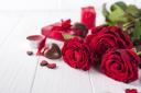 Beautiful red rose and dark chocolate for valentine day on white wooden background, copy space.