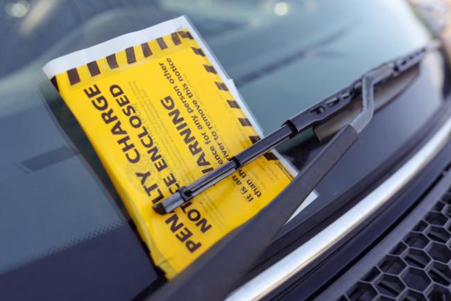 Penalty charge notice parking fine attached to car windscreen.
