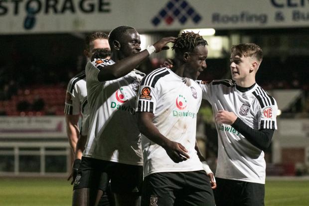 Hereford Times: Victor Sodeinde celebrates Hereford's second goal with a young team-mate. Picture: Andy Walkden/Hereford FC