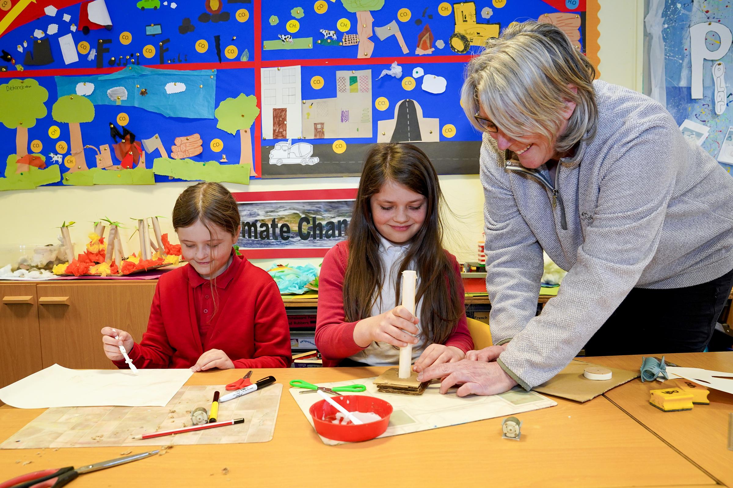 Teacher Linda Willimont shows Eleanor Harris and Jessie Wiggill how to create their own windmill