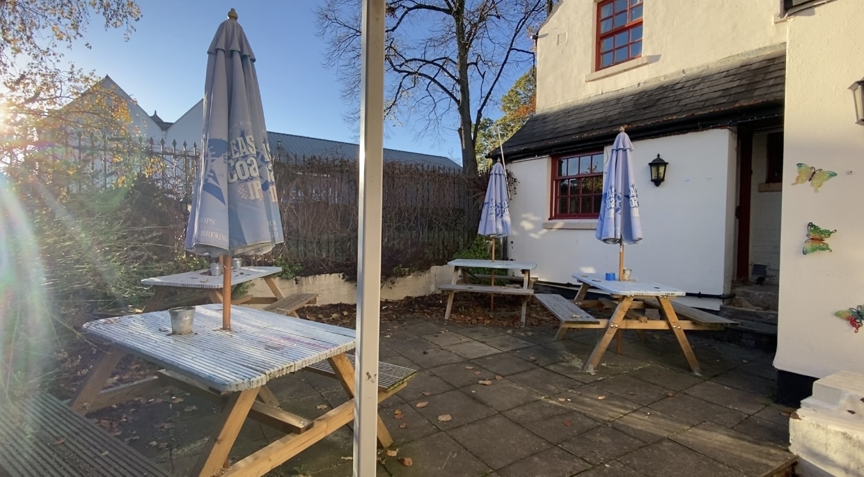 Merton Hotels courtyard with picnic benches, umbrellas, and ash trays