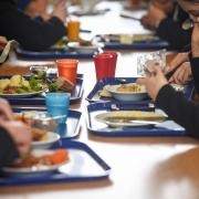 A Hereford school has been praised by Ofsted for giving certain students extra food from the canteen. A view down a table in a school dining hall, with children eating meals from the canteen. Stock picture: PA Wire