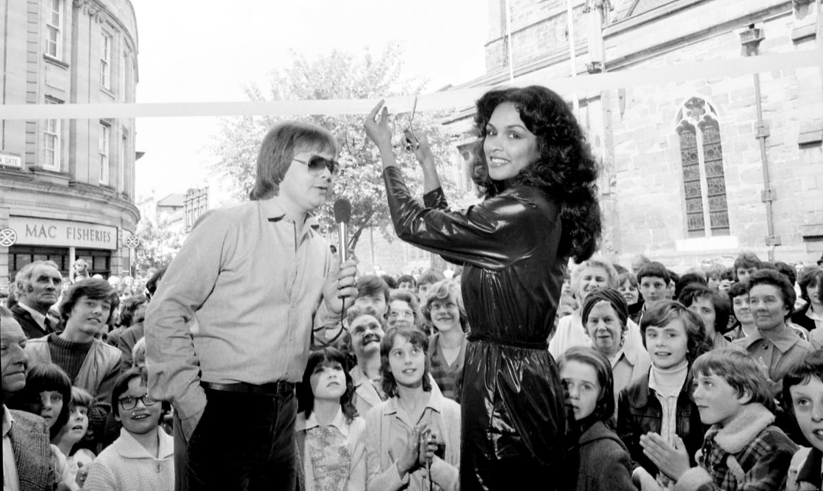 Miss World 1979, Gina Swainson, performs a ribbon cutting in Hereford in 1980 opposite All Saints Church.