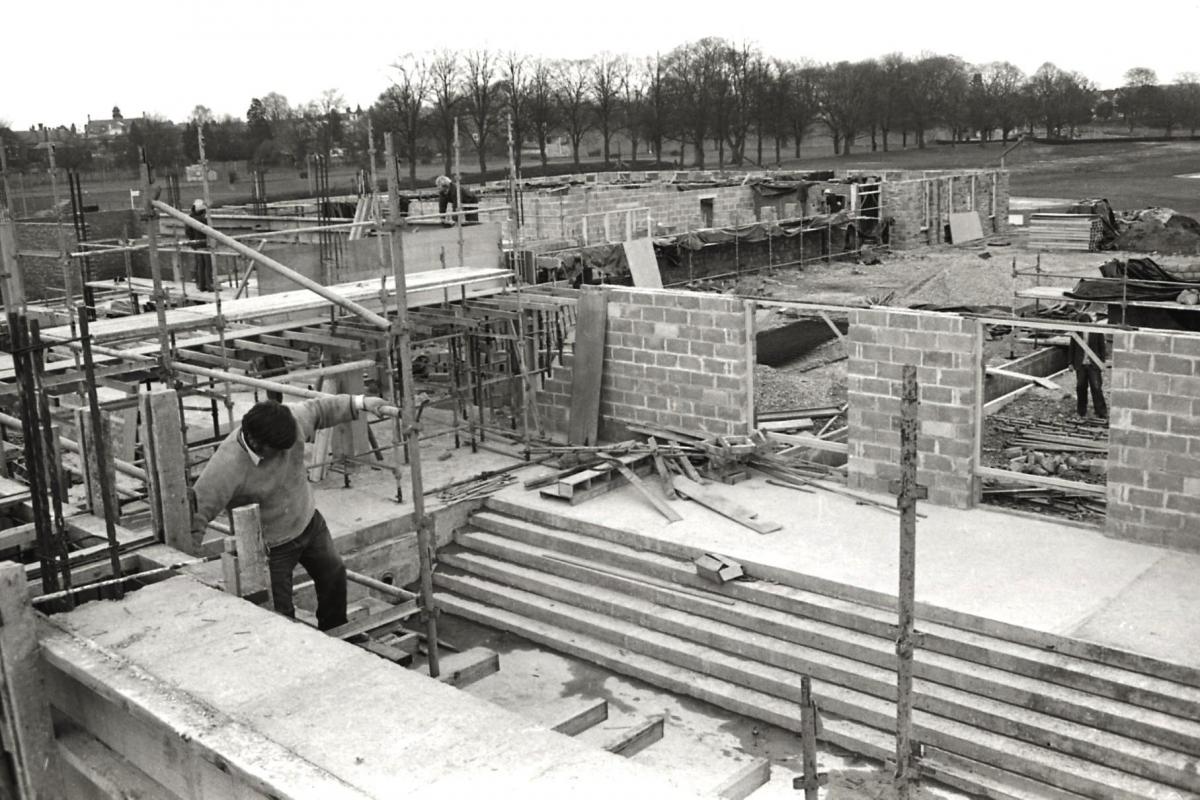 Construction of Hereford Swimming Pool. April 1st 1975. A man working on scaffolding above the familiar steps of the teaching pool.